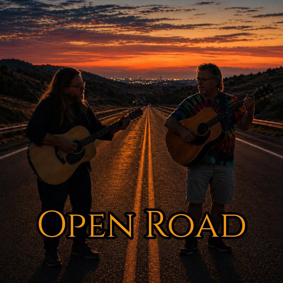 Two guitarists play acoustic guitars on an empty highway at sunset, with a glowing orange sky and distant city lights in the background beneath the title OPEN ROAD.